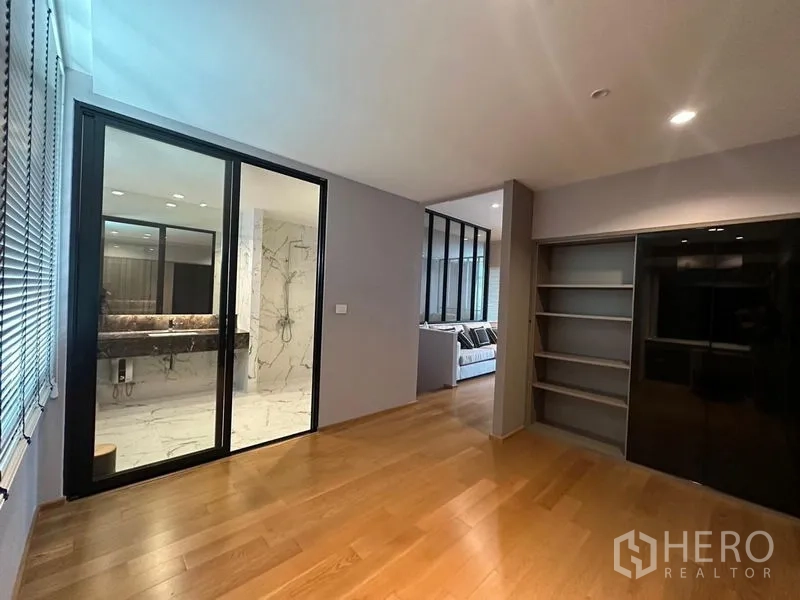 Townhouse for sale in Saphan Sung, Bangkok - Bedroom opening to a marble-clad en‑suite via black-framed sliding glass doors.