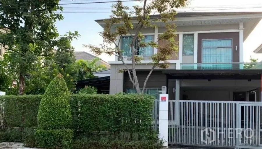 Detached House for sale in Mueang Pathum Thani, Pathum Thani - Front exterior of a two-storey detached house with hedge fence, sliding gate and covered carport.