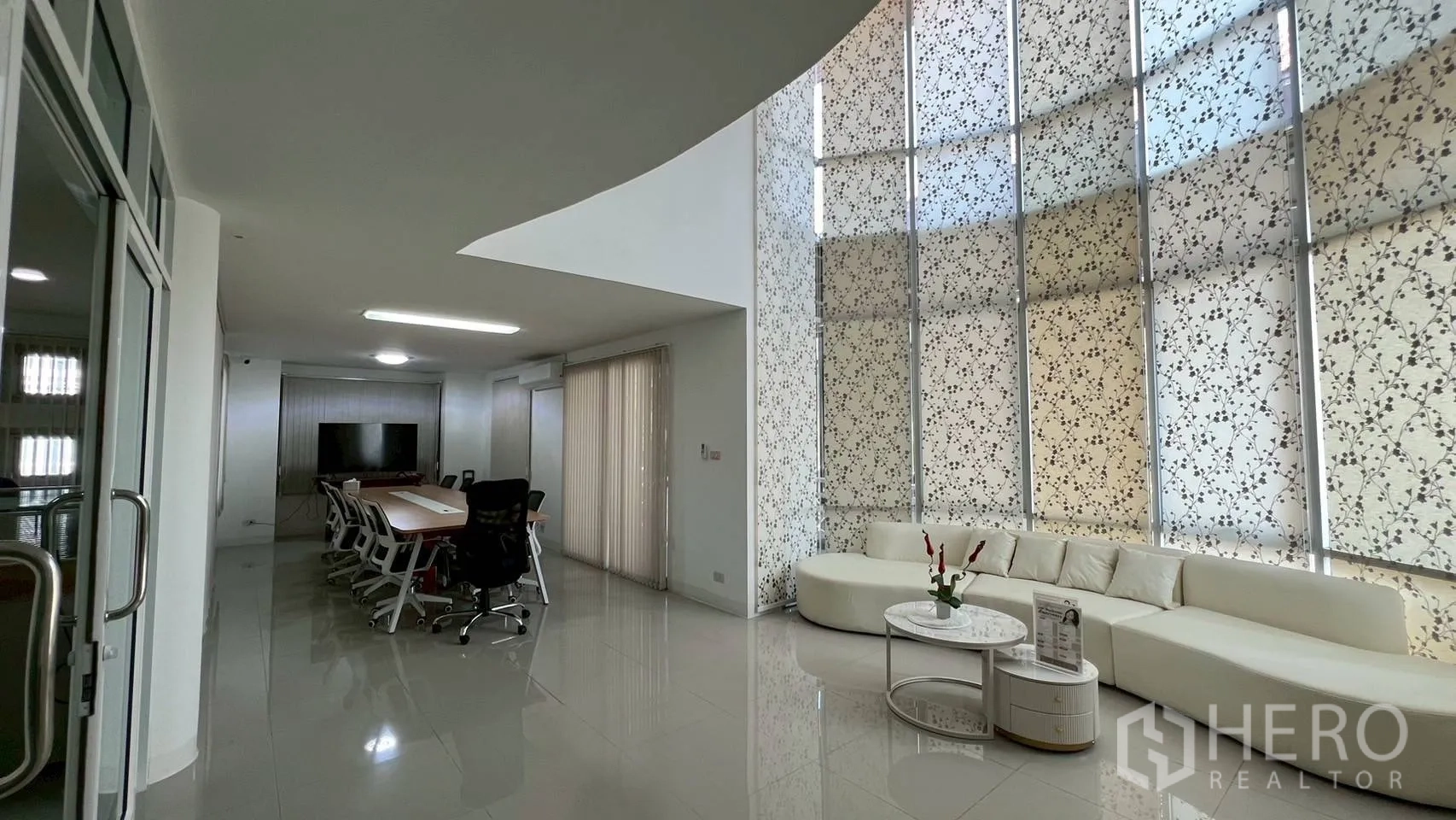 Home Office for rent in Wang Thonglang, Bangkok - Double-height lobby with curved patterned windows, long white sofa and a boardroom table.