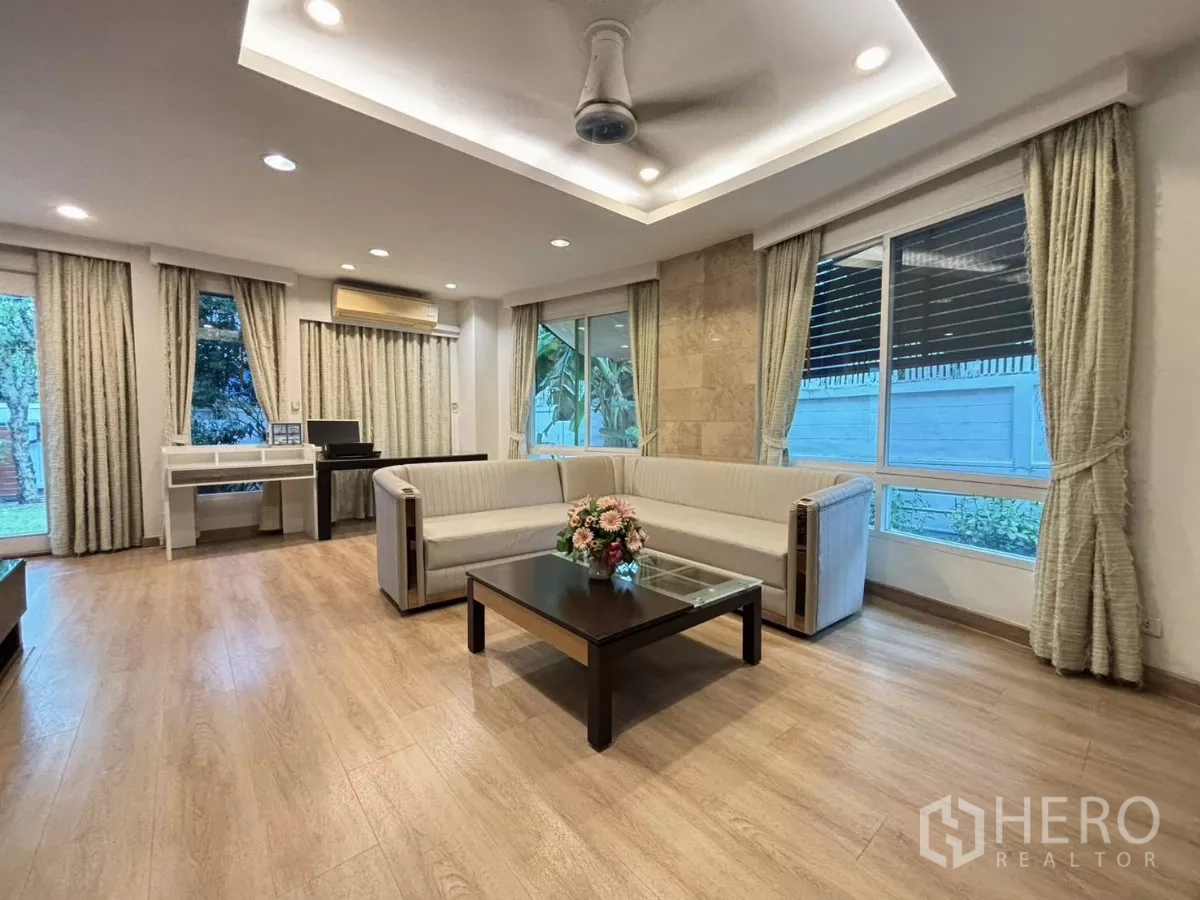 Detached House for rent in Bang Kapi, Bangkok - Airy lounge with U-shaped sofa, corner windows, and soft drapes.