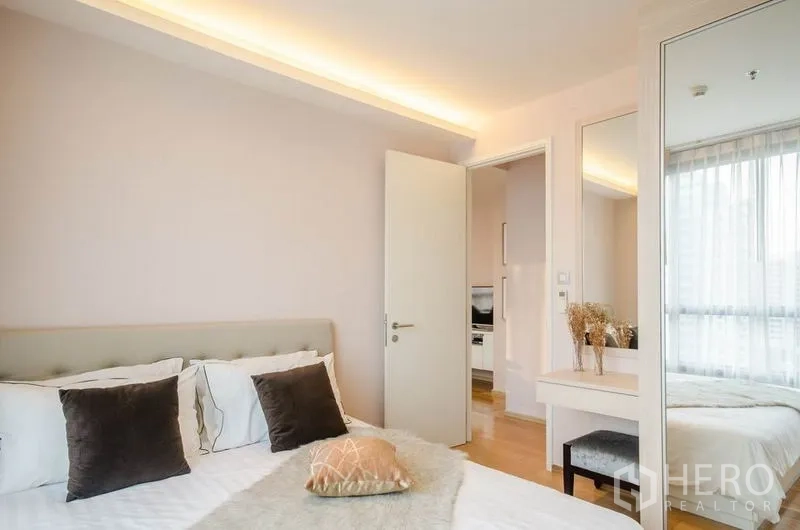 Condominium for rent or sale in Watthana, Bangkok - Cozy master bedroom with soft lighting, vanity and mirrored wardrobe.
