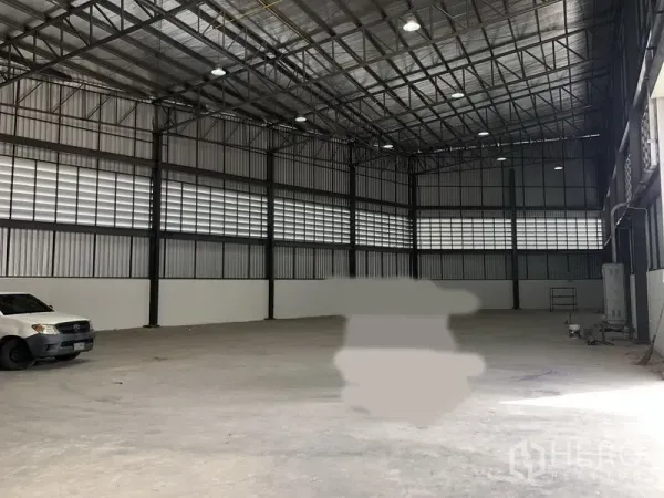 Factory for rent in Samut Prakan - High-ceiling warehouse interior with steel trusses and polished concrete floor.