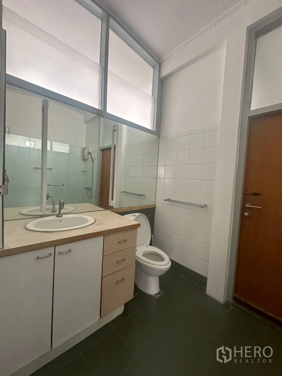 Detached House for rent in Watthana, Bangkok - Bathroom vanity with mirror, sink and toilet beside a glass shower.