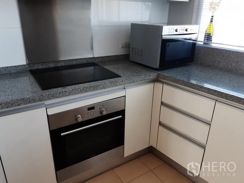 Condominium for rent in Khlong Toei, Bangkok - Kitchen corner with built-in oven, electric cooktop and granite countertops.