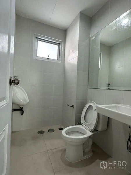 Factory for rent in Mueang Samut Prakan, Samut Prakan - Tiled restroom with toilet, urinal, sink, and ventilation window.