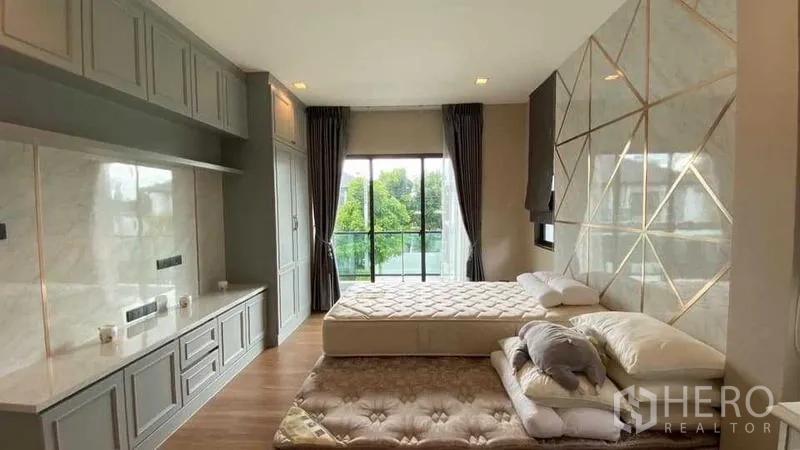 Detached House for sale in Khan Na Yao, Bangkok - Master bedroom with built-in wardrobes, feature wall and large window facing trees.