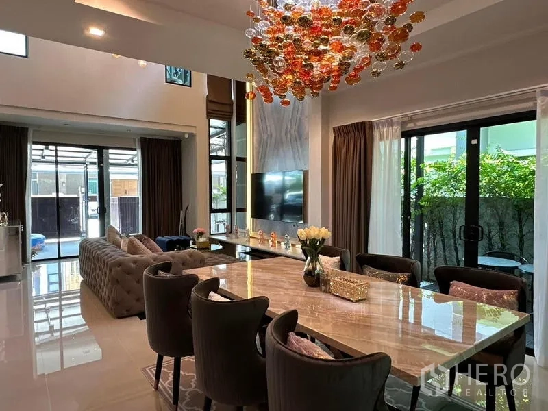 บ้าน ให้เช่าในPrawet, Bangkok - ห้องรับประทานอาหารเชื่อมต่อห้องนั่งเล่น ใต้โคมไฟแชนเดอเลีย มองเห็นสวน