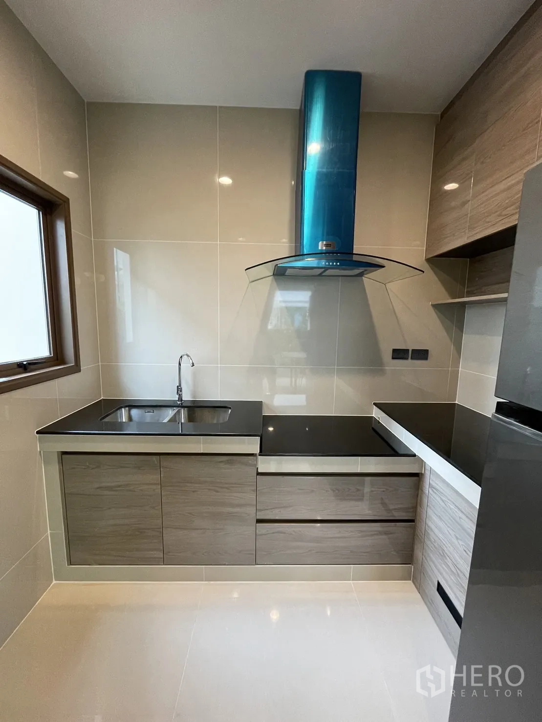 Detached House for rent in Bang Kapi, Bangkok - Compact kitchen with black countertops, sink, stove, and modern hood.