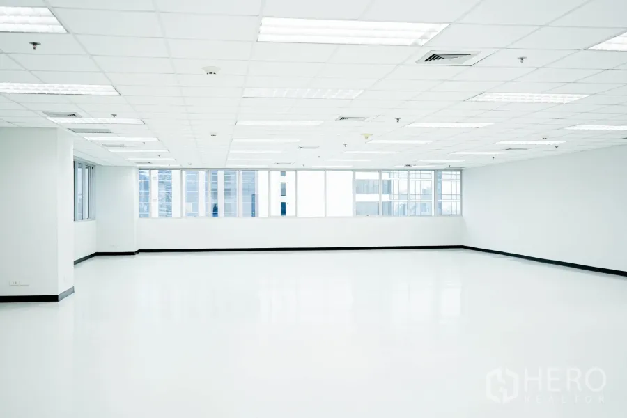 办公空间 出租在Watthana, Bangkok - 空旷办公室，整面窗墙、网格吊顶照明与洁白内饰。