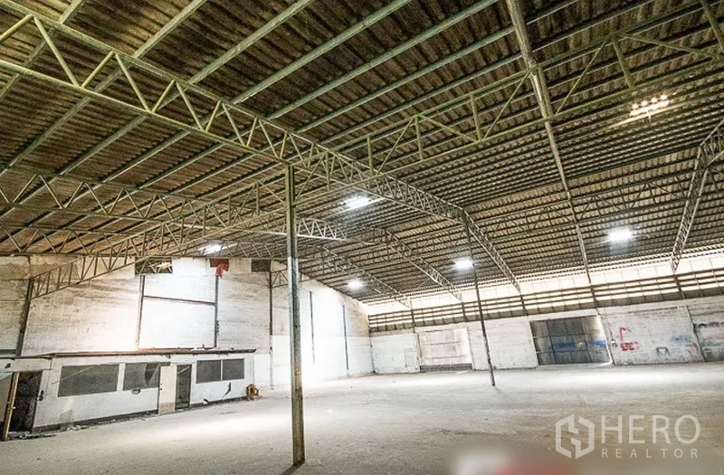Warehouse for rent in Bang Phli, Samut Prakan - Open storage floor with wide column spacing, ventilated metal roof and a small internal office block.