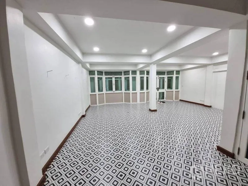 Shophouse for rent in Bang Rak, Bangkok - Expansive tiled space with bay-style windows, supporting columns and bright downlights.