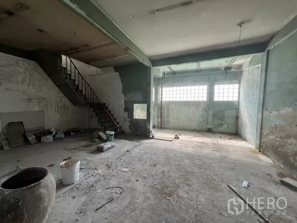 Shophouse for sale in Suan Luang, Bangkok - Raw ground-floor shell with staircase, exposed beams and high windows ready for fit-out.
