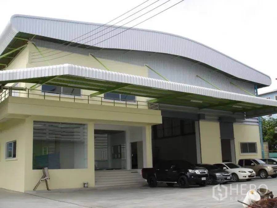 Warehouse for rent in Lat Krabang, Bangkok - Front elevation of the warehouse showing dual roller doors, canopy roof and on-site parking area.