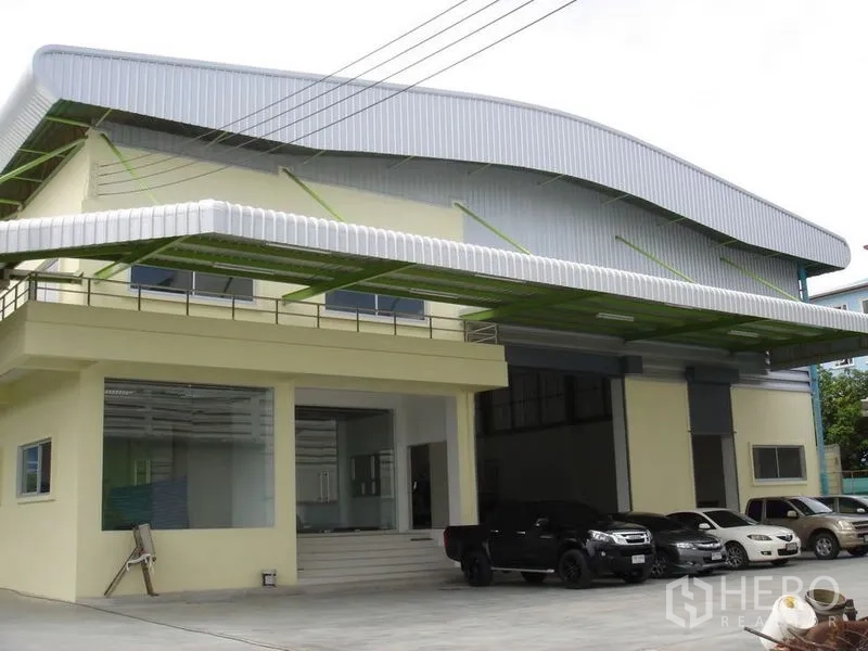 Warehouse for rent in Lat Krabang, Bangkok - Front elevation of the warehouse showing dual roller doors, canopy roof and on-site parking area.