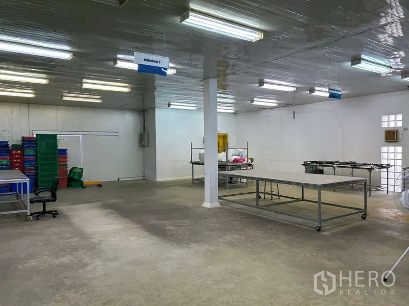 Warehouse for rent in Sam Phran, Nakhon Pathom - Bright open warehouse workspace with fluorescent lighting and concrete floor.