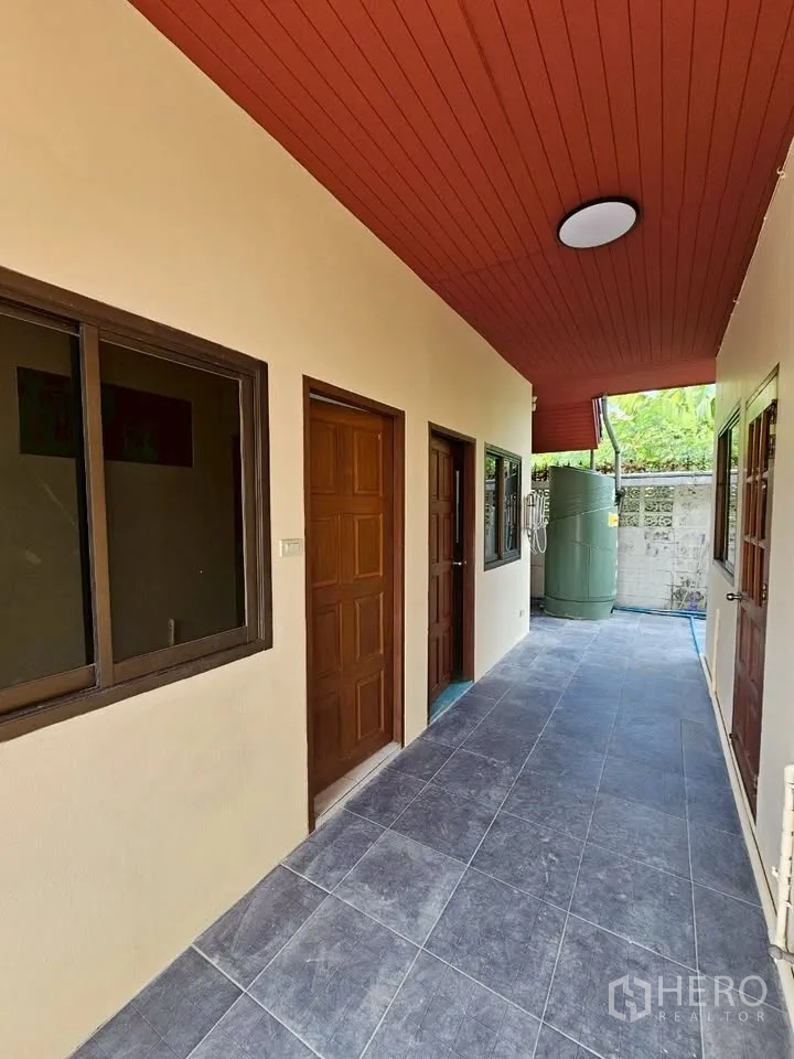 Home Office for rent in Wang Thonglang, Bangkok - Rear corridor with doors and windows under red ceiling and a water tank at the end.