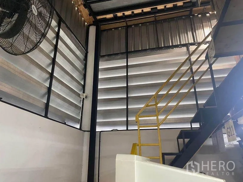 Home Office for rent or sale in Bang Khae, Bangkok - Metal staircase to a mezzanine beside louvered ventilation panels inside the warehouse.