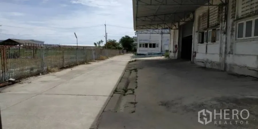 Factory for rent in Chachoengsao - Covered loading bay and concrete driveway beside the factory exterior with a perimeter fence.