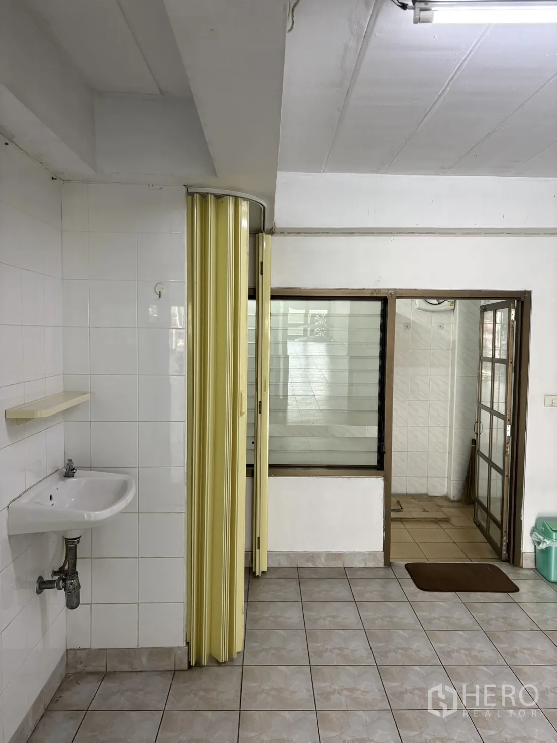 Shophouse for rent in Phra Khanong, Bangkok - Wash area with wall sink, folding partition door and interior window.