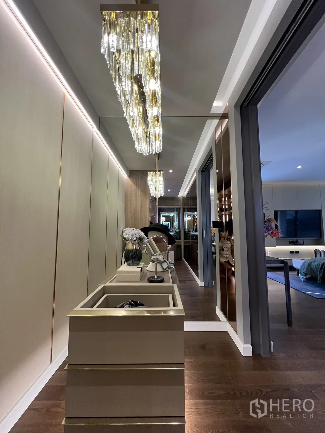 Detached House for sale in Lat Phrao, Bangkok - Hallway with statement chandelier and built-in console leading to a bedroom.