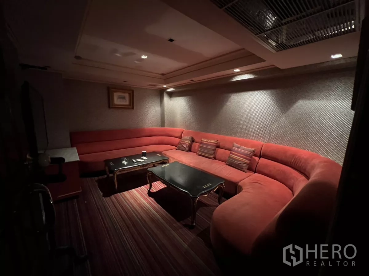 Retail Space for rent in Watthana, Bangkok - Cozy private room with curved red sofa, striped carpet and coffee table.