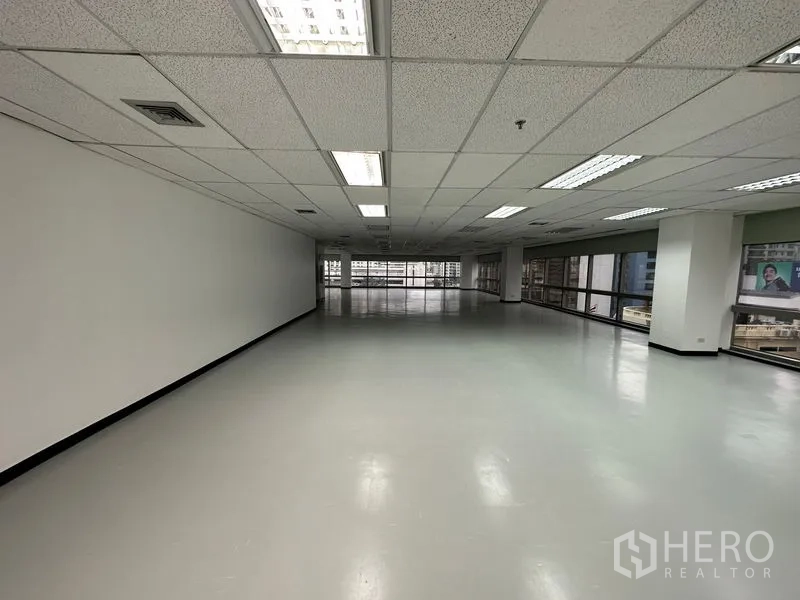 Office Space for rent - Deep rectangular office plate with windows at both ends and overhead fluorescent fixtures.
