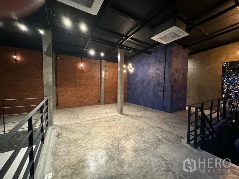 Standalone for rent in Sathon, Bangkok - Open-plan interior with exposed brick feature wall, concrete columns, spot lighting and ducted ceiling air-conditioning.