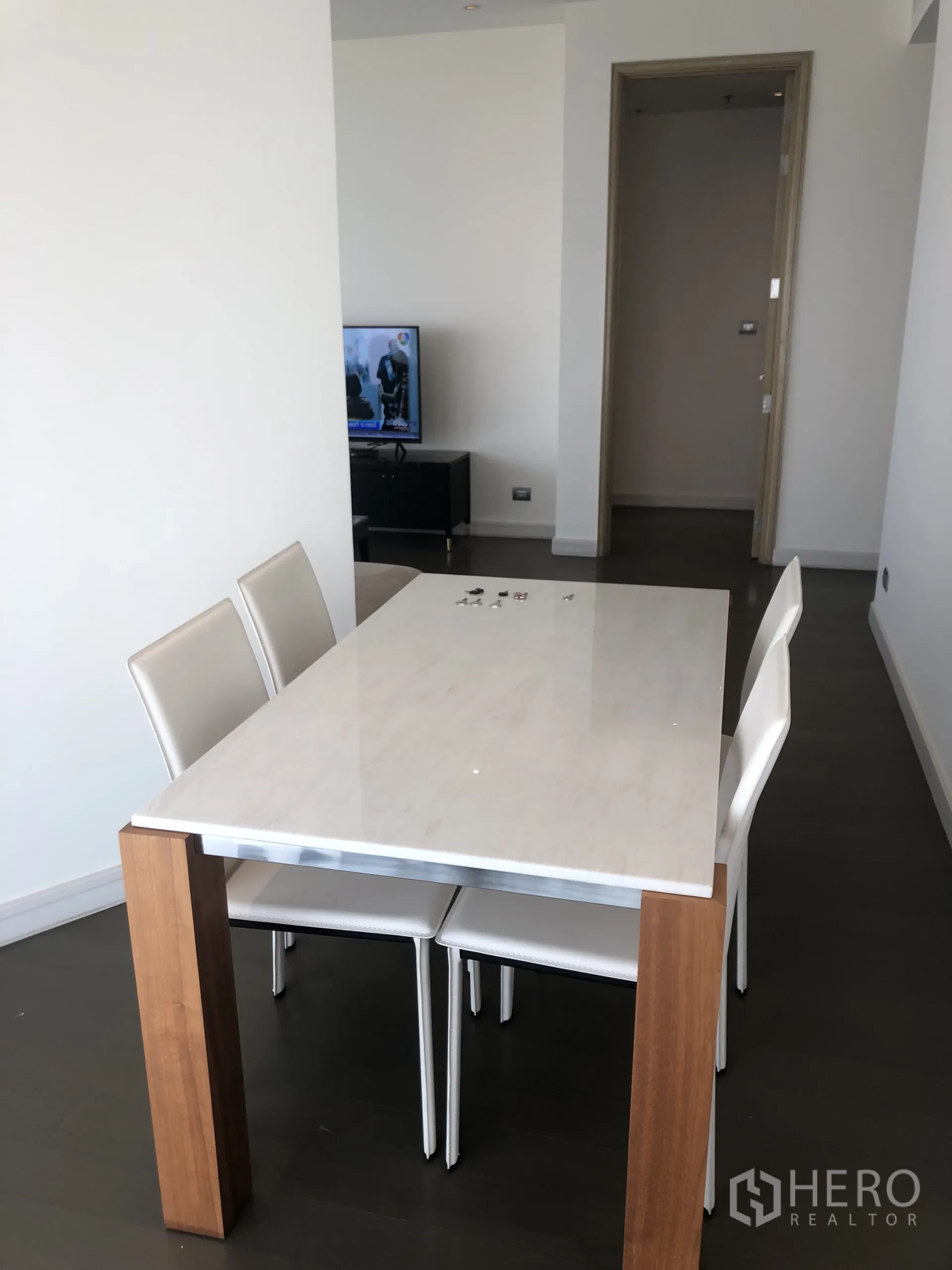 Condominium for rent in Pathum Wan, Bangkok - Dining area with marble-top table and four chairs next to the corridor and living space.