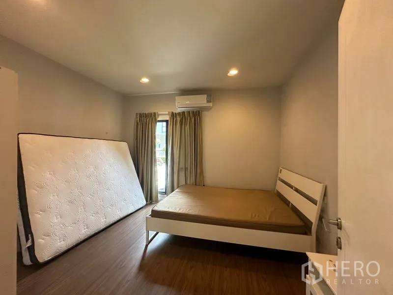 Detached House for rent in Lam Luk Ka, Pathum Thani - Bright bedroom with bed, balcony door, curtains and air conditioner.
