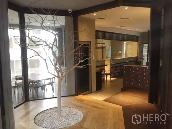 Retail Space for rent in Khlong Toei, Bangkok - Entrance foyer with glass partitions and a decorative indoor tree next to the seating area.