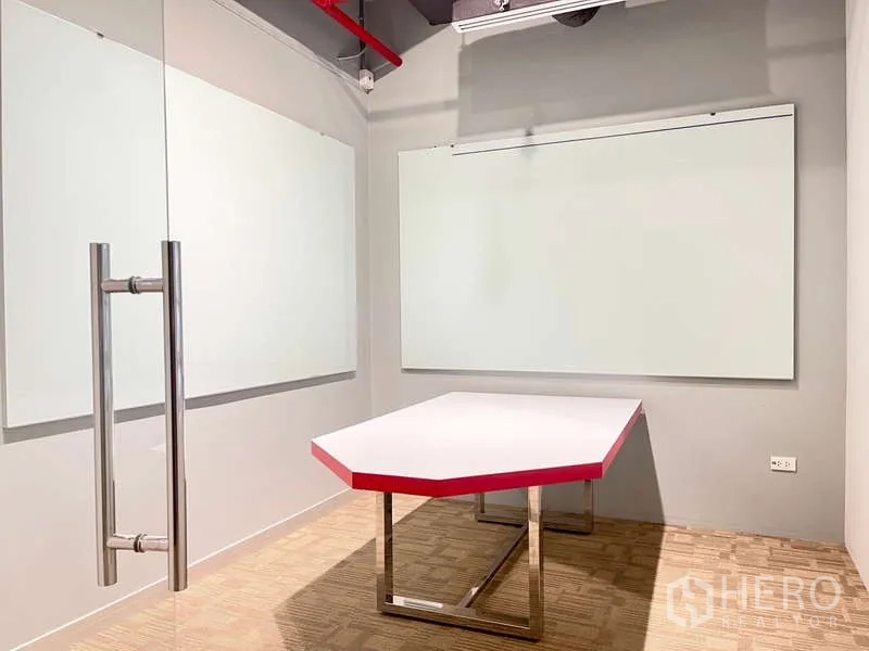 Office Space for rent in Watthana, Bangkok - Compact meeting room with two whiteboards, glass door and a geometric table with red edge.