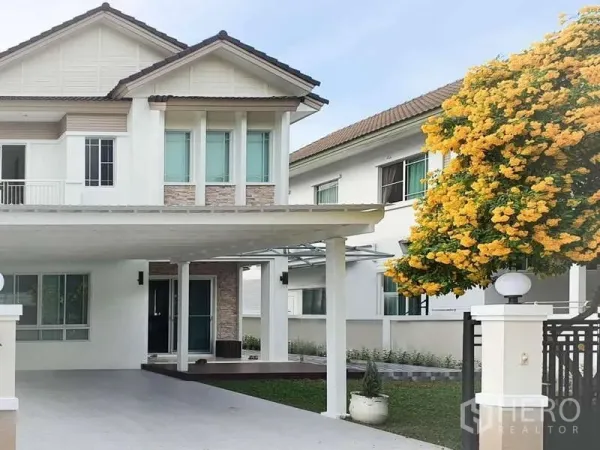 Detached House for rent in Sathon, Bangkok - Two-storey white detached house in Sathon with a covered carport and a blooming yellow tree at the gate.