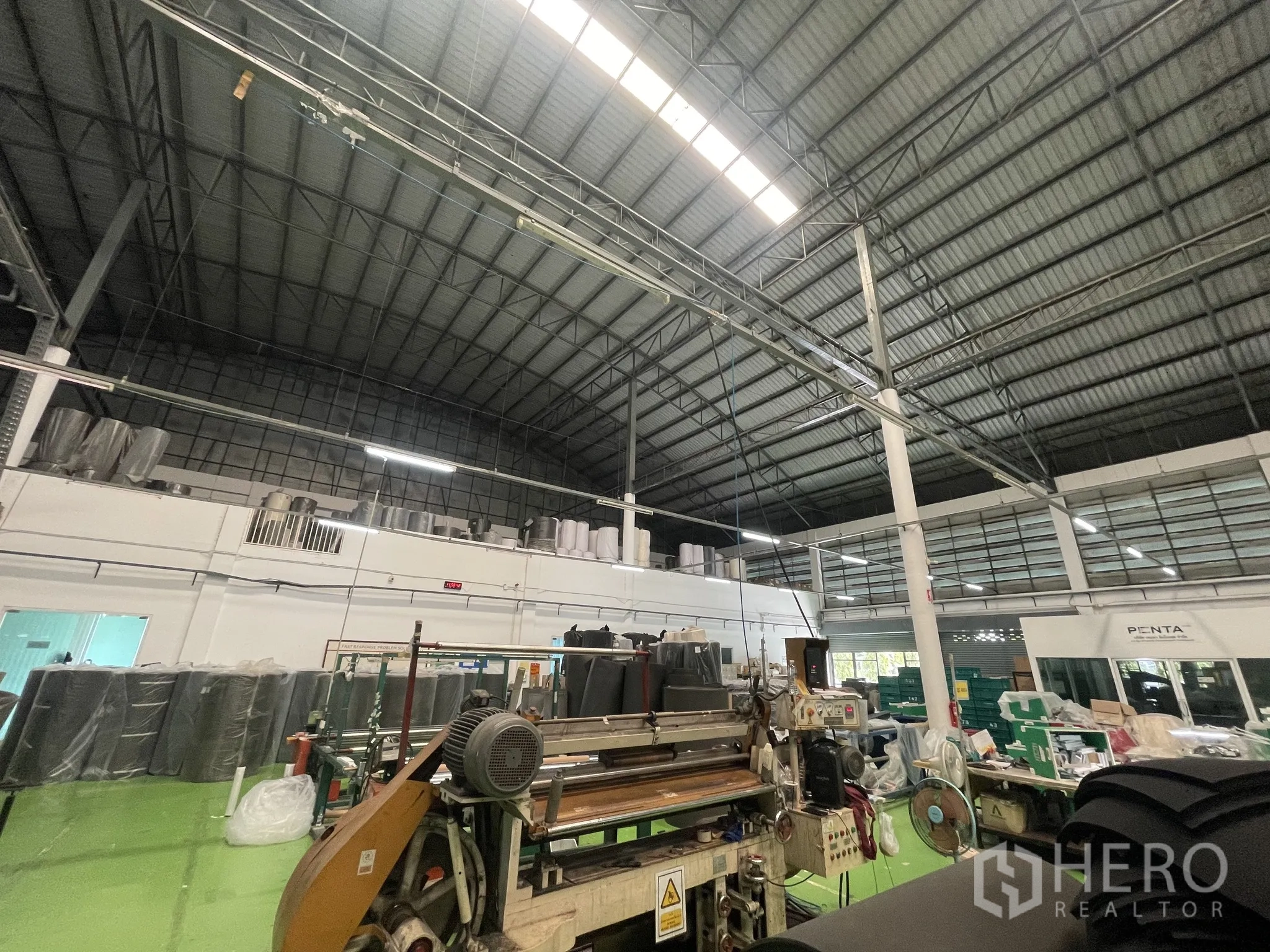 Warehouse for sale in Lat Lum Kaeo, Pathum Thani - High‑clearance production hall with steel truss roof, skylights and industrial machinery.