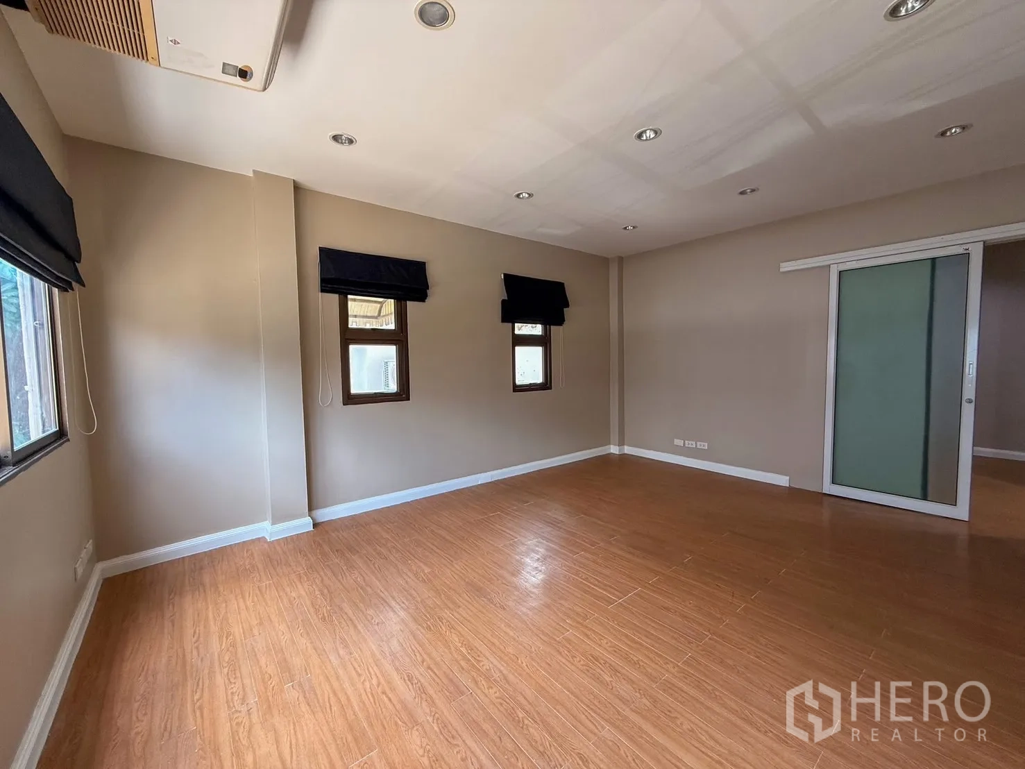 Home Office for rent in Wang Thonglang, Bangkok - Empty office room with wood-style flooring, recessed lights and small windows.