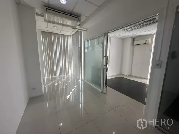办公空间 出租在Huai Khwang, Bangkok - 走廊连接多间私密办公室，配滑动玻璃门、竖百叶与筒灯。