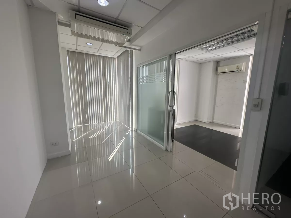 办公空间 出租在Huai Khwang, Bangkok - 走廊连接多间私密办公室，配滑动玻璃门、竖百叶与筒灯。