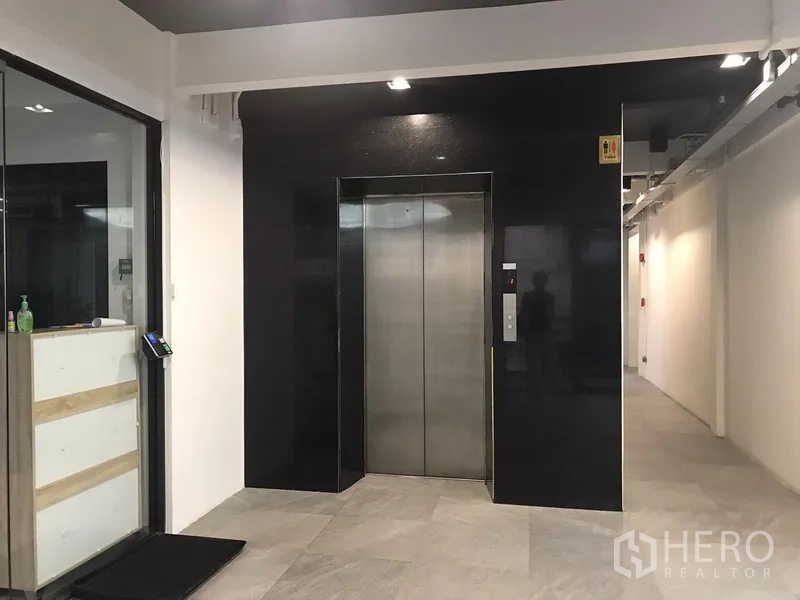 办公空间 出租在Khlong Toei, Bangkok - 现代走廊与不锈钢电梯，地面为瓷砖。