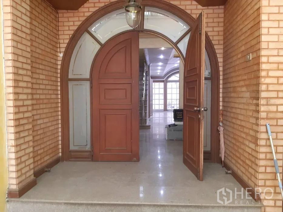 Townhouse for rent in Khlong Toei, Bangkok - Arched wooden front door and foyer with brick walls and a hanging light.