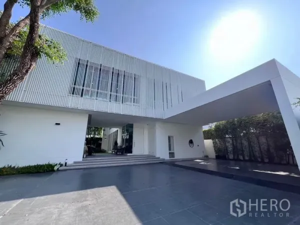 独立式住宅 出售在Samut Prakan - 现代两层白色独栋别墅，竖向格栅立面与遮雨车棚。