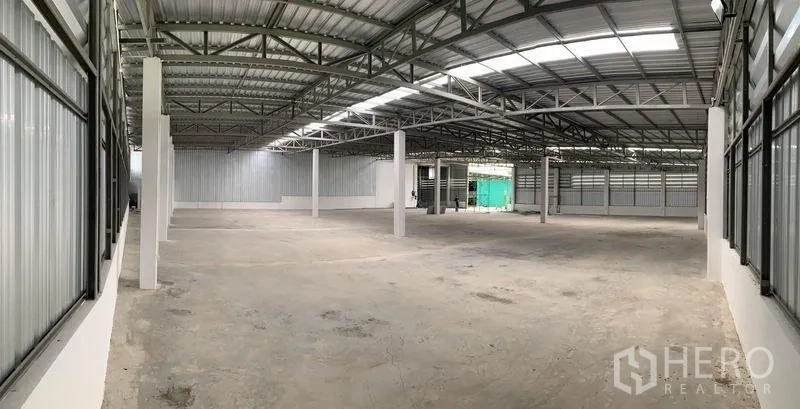 Warehouse for rent in Mueang Pathum Thani, Pathum Thani - Panoramic view of a large open-plan warehouse with high ceiling, structural columns and metal siding.