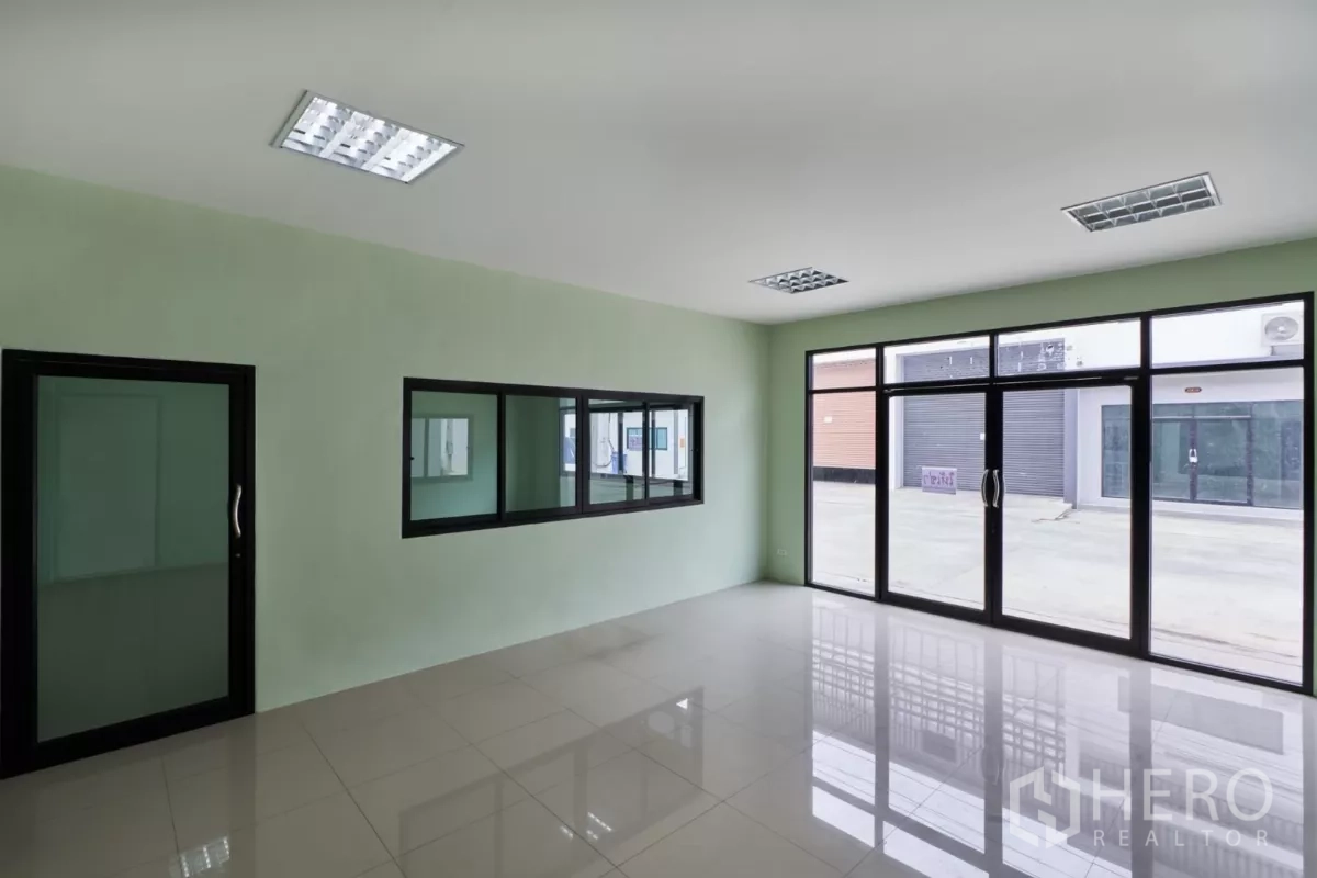 Factory for rent in Mueang Samut Sakhon, Samut Sakhon - Ground-floor office with full-height glass frontage and glossy tiled flooring.