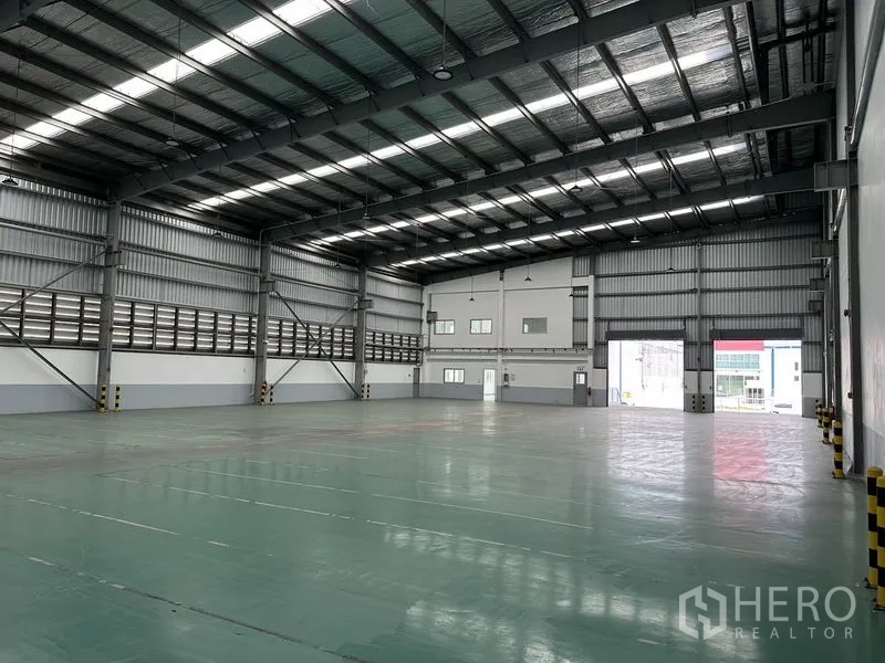 Factory for rent in Mueang Samut Prakan, Samut Prakan - Open production area with steel structure, natural light panels, and roller shutter access.