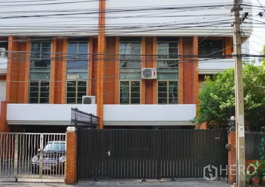 联排别墅 出租在Pathum Wan, Bangkok - 砖砌联排别墅外立面，落地窗与黑色大门。