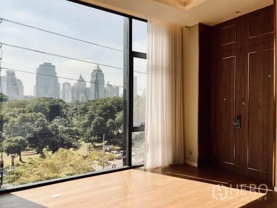 Condominium for sale in Pathum Wan, Bangkok - Bedroom corner with full-height window, sheer curtains and green park outlook.