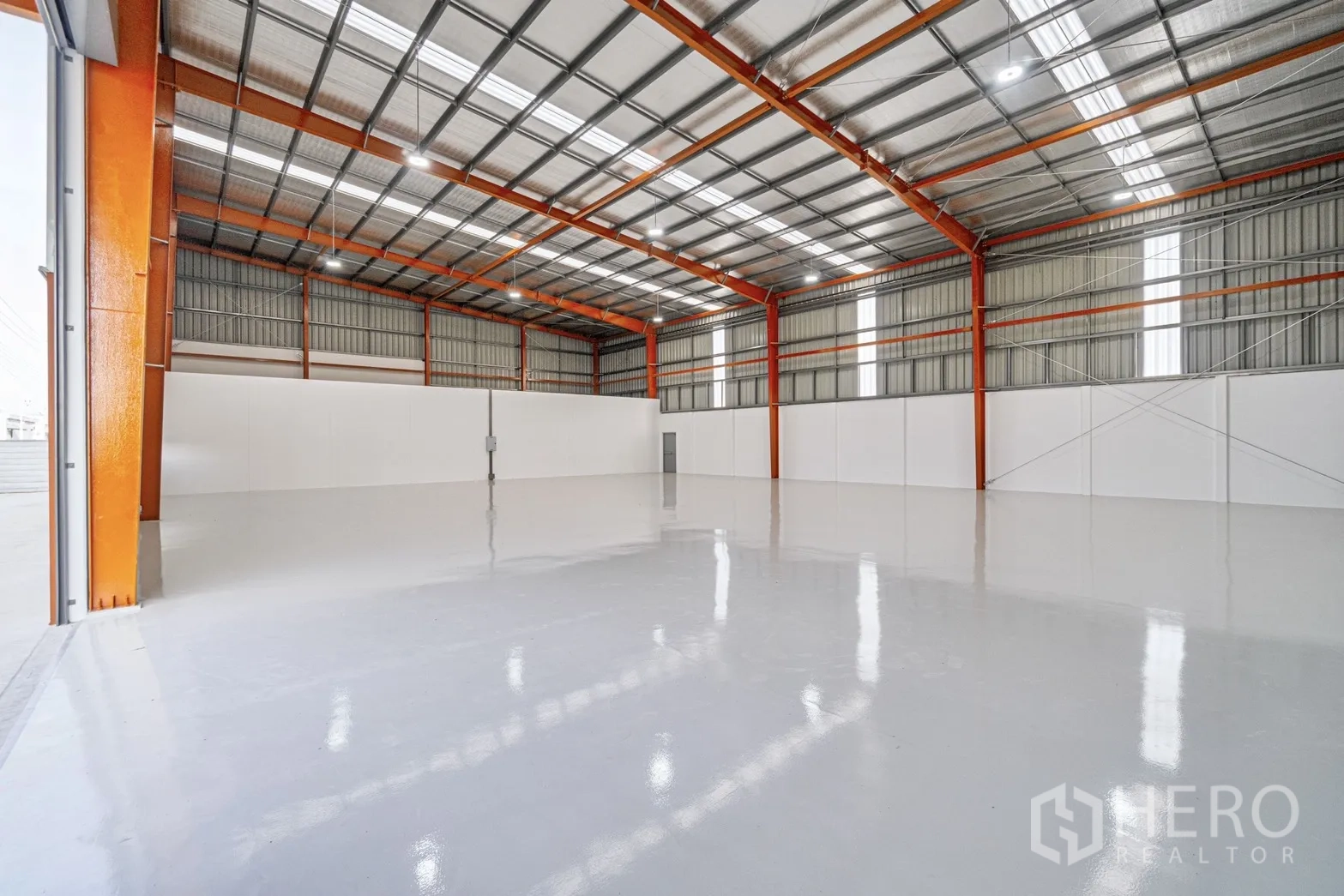 Factory for rent or sale in Lam Luk Ka, Pathum Thani - Spacious warehouse interior with high steel roof, orange columns and glossy white floor.