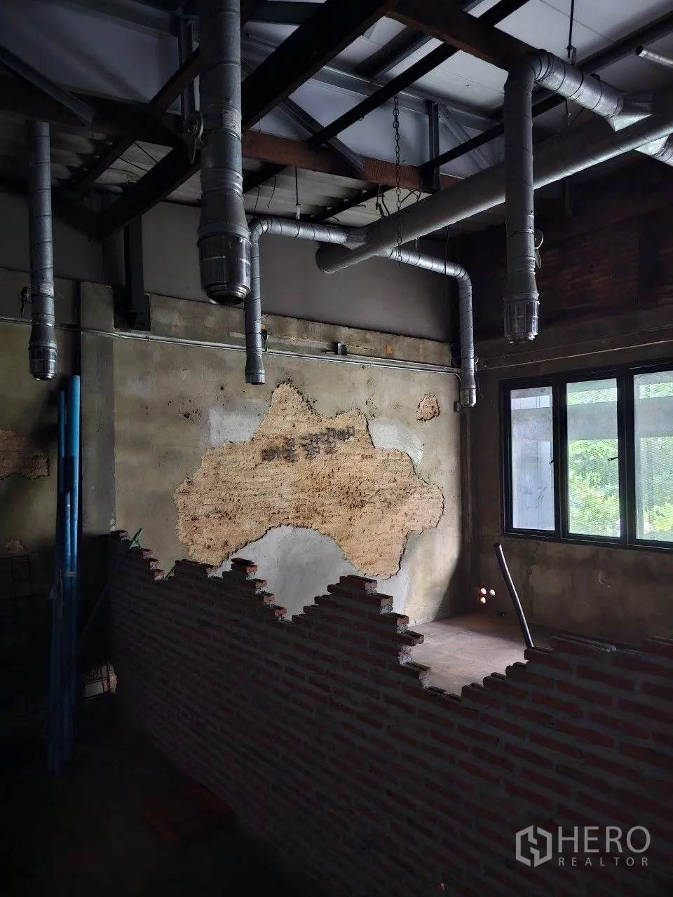 Shophouse for rent or sale in Watthana, Bangkok - Room with half-height brick divider, rough plaster wall, and multiple exhaust ducts.