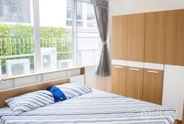 Townhouse for rent in Khlong Toei, Bangkok - Ground-floor bedroom with large windows, fitted wardrobes, and a garden outlook.