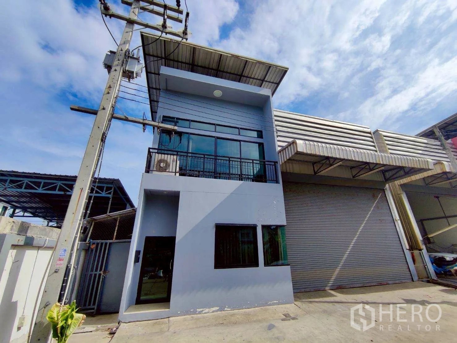 仓库 for rent in Lam Luk Ka, Pathum Thani - 临街视角的仓库外观，设有卷闸门与阳台。
