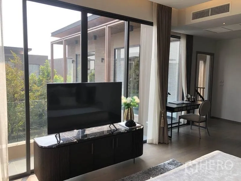 Detached House for sale in Bang Kapi, Bangkok - Master suite corner with TV console, full-height windows, balcony and study nook.