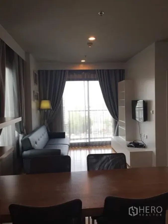 Condominium for rent in Watthana, Bangkok - Bright living room with sofa, TV wall and balcony doors in a Watthana condo near BTS On Nut